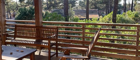 A wooden deck with benches and a table, surrounded by trees.
