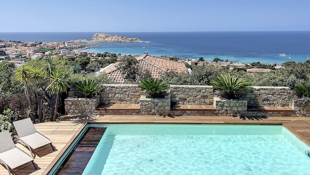 Piscina com vista para o mar e uma cidade ao fundo.