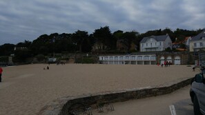 Ein Strand mit einer Steinmauer und einem Gebäude mit vielen Fenstern im Hintergrund.