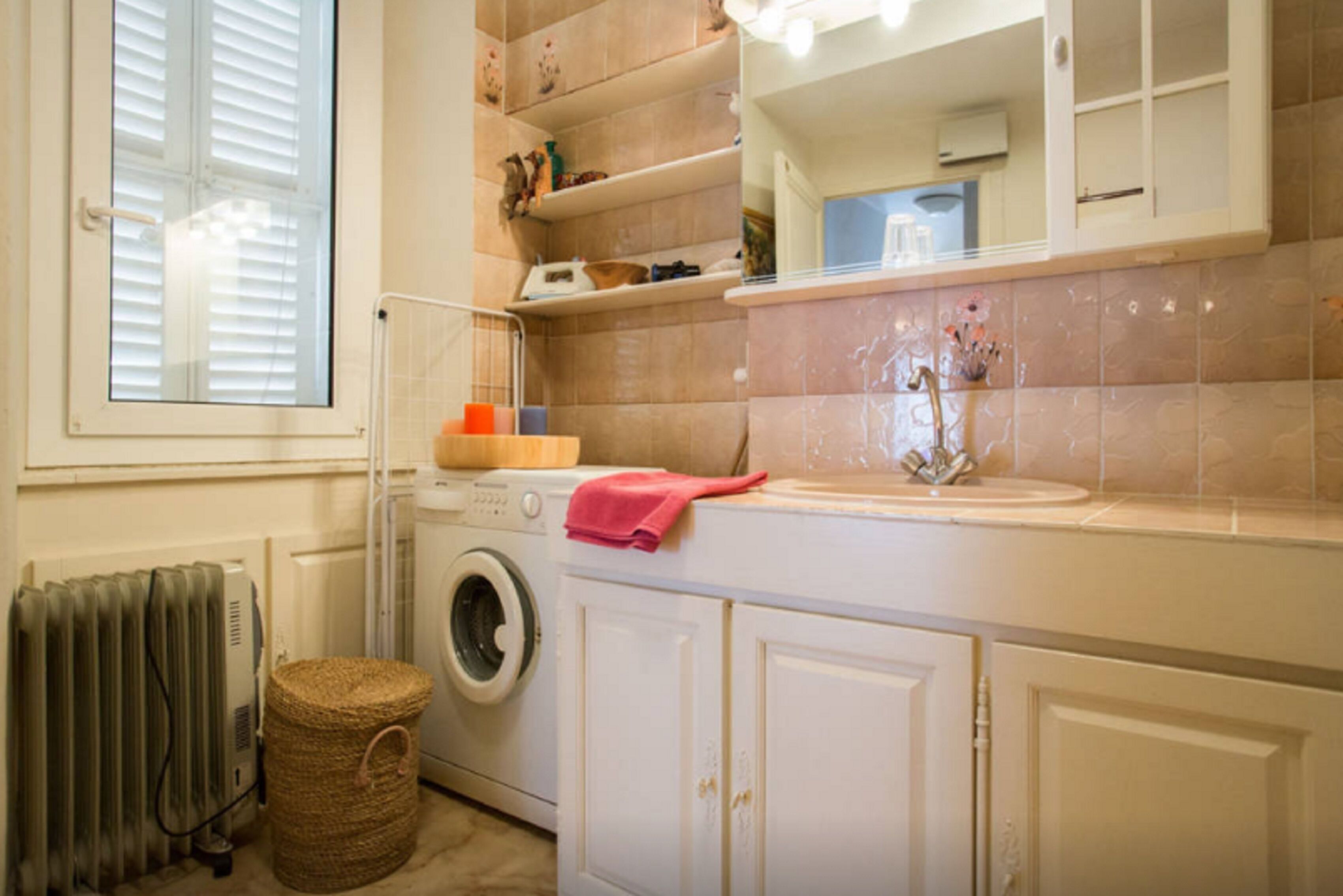 A laundry area with a washing machine, a drying rack, and a basket.