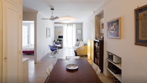 Un comedor con una mesa de madera, sillas, un ventilador de techo y una estantería.