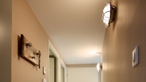 Un pasillo con piso de madera, paredes color beige y una puerta al final.