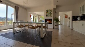 Eine moderne Küche mit Essbereich, großen Fenstern und einem Kamin.