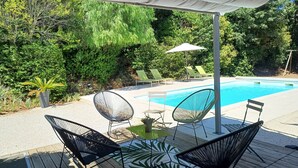 Ein Poolbereich mit überdachter Sitzgelegenheit, Liegestühlen und einem Pool.