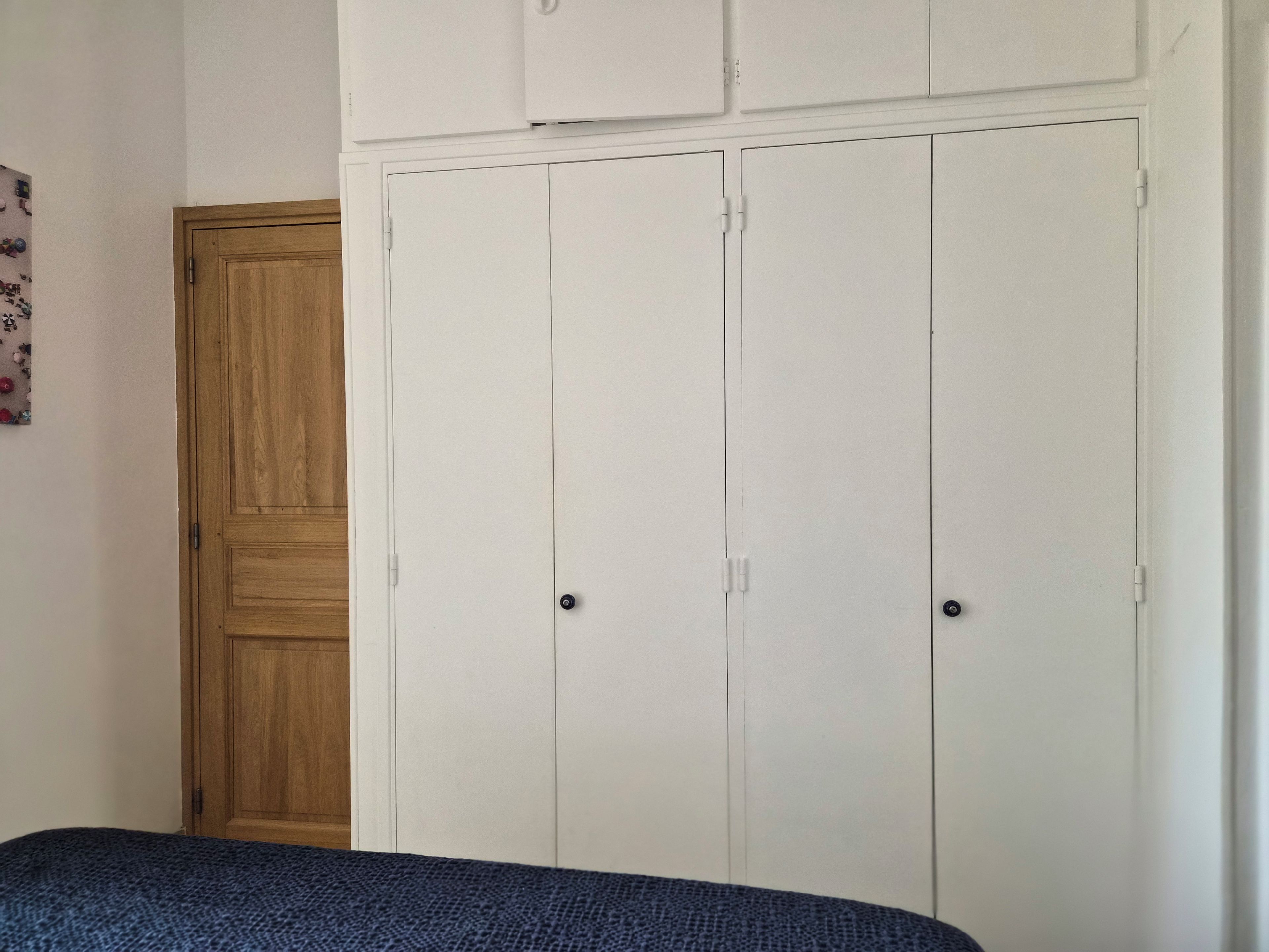A bedroom with a bed, a wardrobe, and a wooden door.