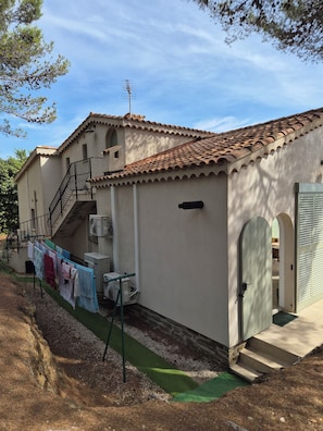 A building with a tiled roof, a staircase, and a small outdoor area with a clothesline.