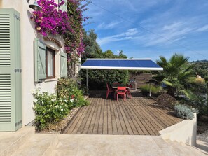 Eine Terrasse mit Tisch und Stühlen, einem überdachten Bereich und einem Holzdeck.