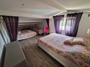 Ein Zimmer mit zwei Betten, einem Sessel und einem fenster mit Vorhängen.