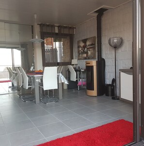 Une cuisine moderne avec un coin repas, dotée d’une grande fenêtre, d’une cheminée et d’un tapis rouge.