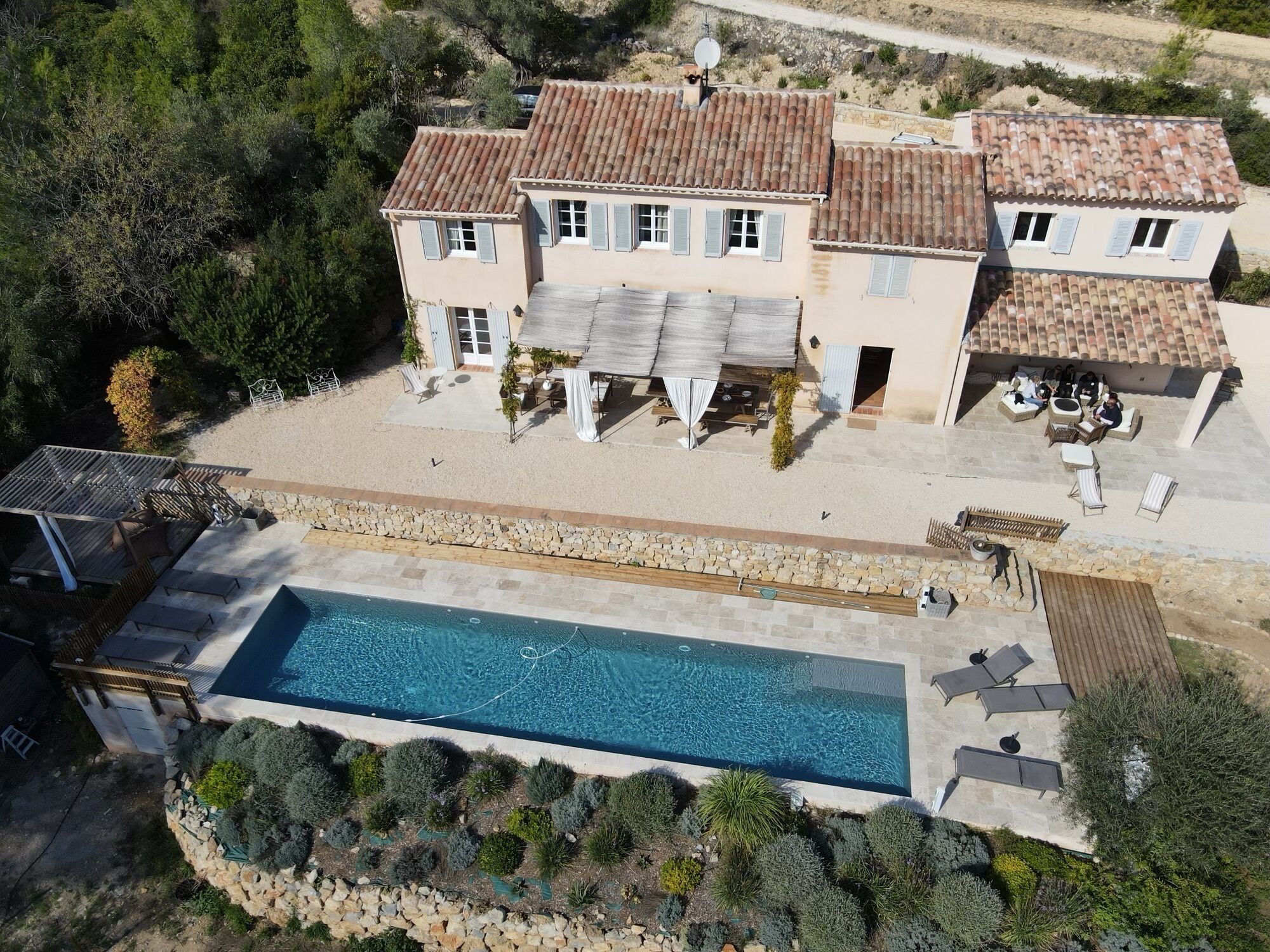 A two-story house with a swimming pool, outdoor seating, and a garden.