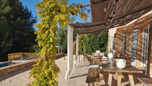 Un patio con pérgola, mobiliario exterior y una piscina.