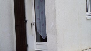 Un bâtiment blanc avec une porte entrouverte et une fenêtre avec un rideau.