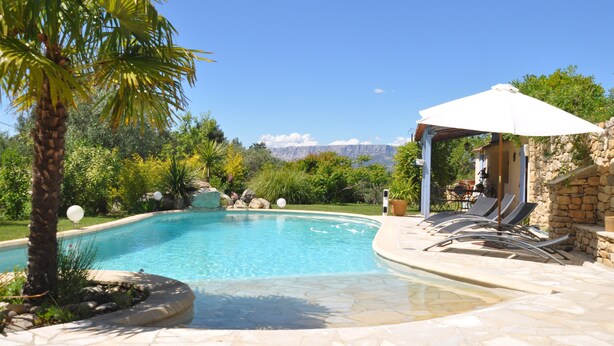 A pool with a stone deck, lounge chairs, and a pergola with an umbrella. - Exceptional - Property with full view of Mont Ste Victoire (Trets)