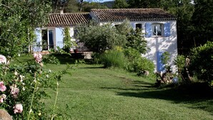 A white building with blue shutters, surrounded by a well-maintained garden with roses and trees. - Exceptional - Property with full view of Mont Ste Victoire (Trets)