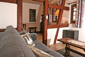 A cozy living room with a grey sofa, wooden beams, a small table, and a cabinet. - Coquette timbered house of the 17th century renovated (Eguisheim)