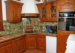 A kitchen with wooden cabinets, a dishwasher, and a coffee maker. - Coquette timbered house of the 17th century renovated (Eguisheim)