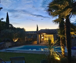 A poolside view of a house with a stone exterior, a visible door, and a small patio area.