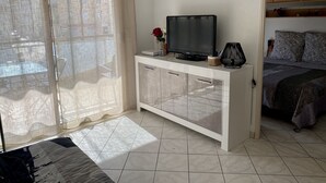 Une pièce avec un meuble blanc, un téléviseur et un lit recouvert d’une literie à motifs.