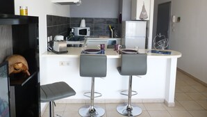 A modern kitchen with a central island, bar stools, a microwave, a refrigerator, and a toaster.