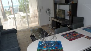 A living room with a sofa, a TV, a fan, and a table with artwork.