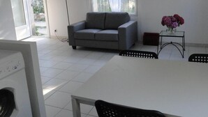 Una sala de estar moderna con un sofá gris, una mesa de comedor con sillas y un jarrón con flores.