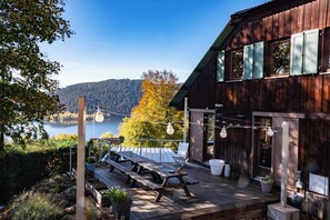 A wooden deck with picnic tables, potted plants, and string lights. - Panoramic lake view (600m)! ATYPIQUE Chalet ARCHITECTE--View VIDEO DRONE (Gérardmer)