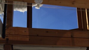 Una ventana con marco de madera que ofrece vistas a un paisaje nevado, con árboles y montañas distantes.