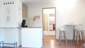 Een moderne keuken met een koffieapparaat, een klein eiland en een eethoek met twee witte stoelen.