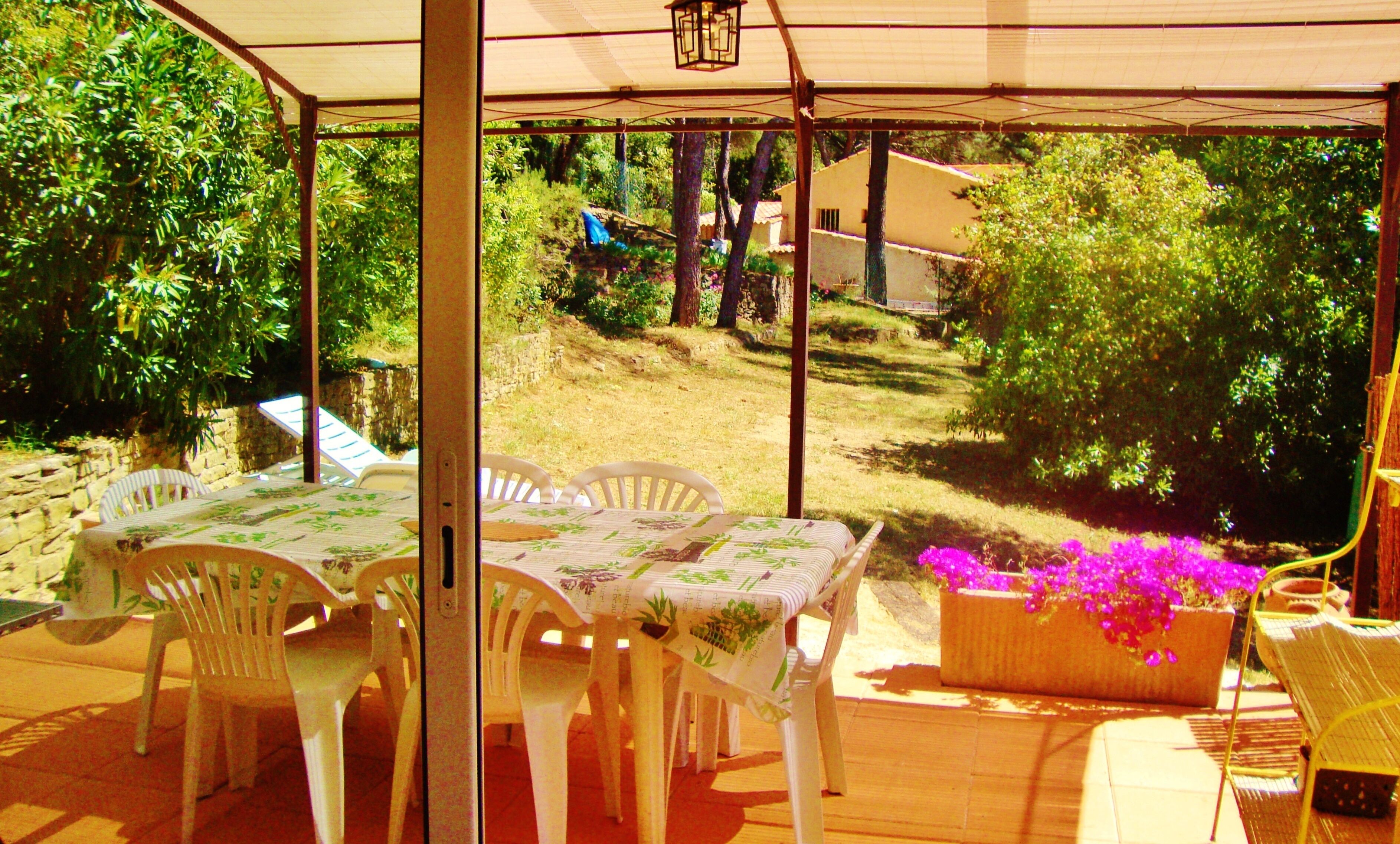 Une terrasse extérieure avec une table et des chaises, entourée de verdure et offrant une vue sur un quartier résidentiel.