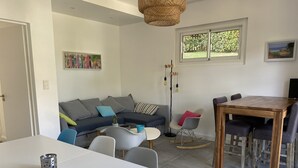A modern living room with a white dining table, grey sofa, and a wooden dining table with chairs. - Lake view, Exceptional location between Lake and Ocean, all within walking distance (Soorts-Hossegor)