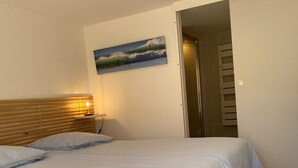 A bedroom with a bed, wooden headboard, a painting, and a nightstand with a lamp. - Lake view, Exceptional location between Lake and Ocean, all within walking distance (Soorts-Hossegor)