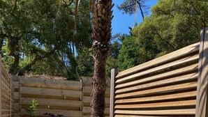 A wooden deck with a palm tree, surrounded by a wooden fence and gravel. - Lake view, Exceptional location between Lake and Ocean, all within walking distance (Soorts-Hossegor)