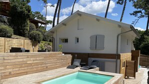 A wooden deck with a rectangular pool, lounge chairs, and a small building with a white facade and wooden accents. - Lake view, Exceptional location between Lake and Ocean, all within walking distance (Soorts-Hossegor)