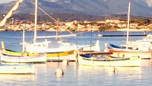 A marina with several boats docked, calm water, and a mountainous backdrop.