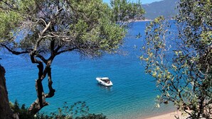 A coastal landscape with a boat on the water, rocky terrain, and a clear sky.