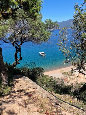 Eine Küstenlandschaft mit einem Boot auf dem Wasser, felsigem Gelände und blauem Himmel.