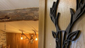 Un lit en bois avec un plaid en fourrure, une chaise en bois et une décoration murale représentant une tête de cerf.