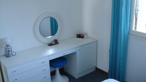 A compact bedroom with a white dresser, a round mirror, a blue stool, and a bed. - cap d'agde t3 apartment 54m2 facing the sea seafront with sea views (Agde)