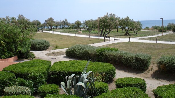 A park with a paved walkway, benches, and well-maintained greenery. - cap d'agde t3 apartment 54m2 facing the sea seafront with sea views (Agde)