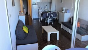 A compact living space with a sofa, a dining table with chairs, a kitchenette, and a small kitchen area. - cap d'agde t3 apartment 54m2 facing the sea seafront with sea views (Agde)