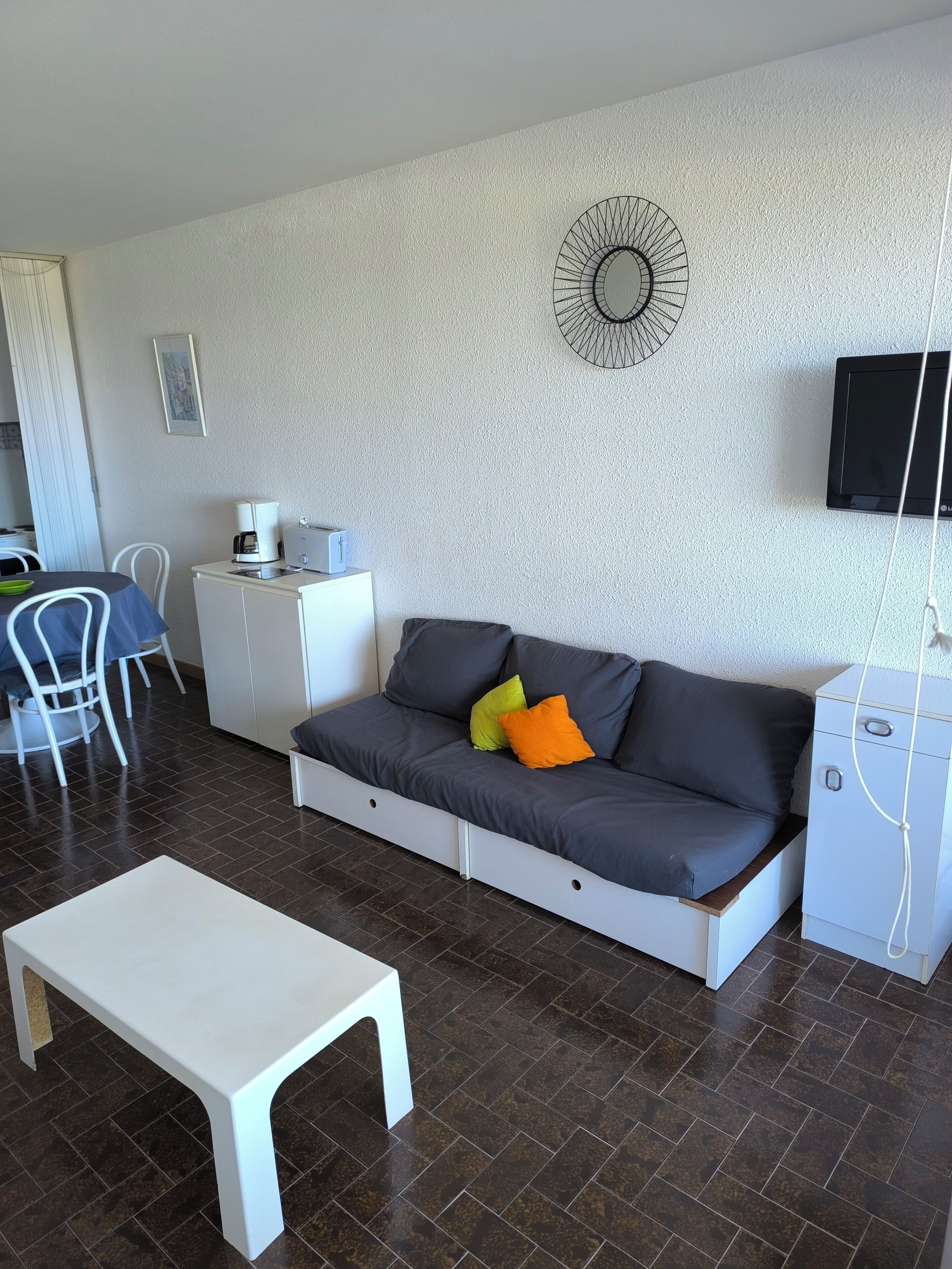 A modern living room with a grey sofa, a white coffee table, and a TV mounted on the wall.