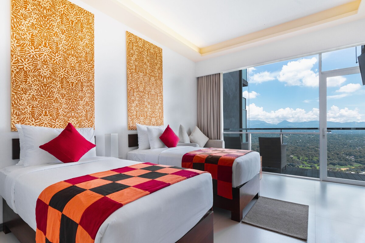 A hotel room with two beds, a large window with a city view, and a patterned wall.