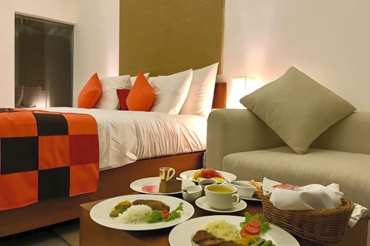 Ett hotellrum med en säng, en soffa och ett matbord där frukosten är dukad.