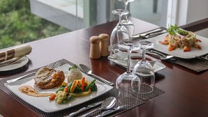 A dining table set with plates of food, cutlery, and wine glasses.