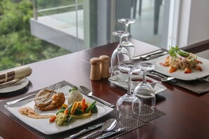 A dining table set with plates of food, cutlery, and wine glasses.