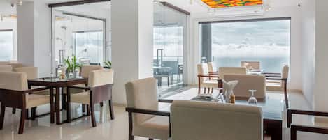A modern dining area with a large table, chairs, and a view of the sky.