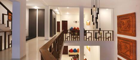 A multi-level interior with a staircase, a dining area with colorful cushions, and decorative wall art.