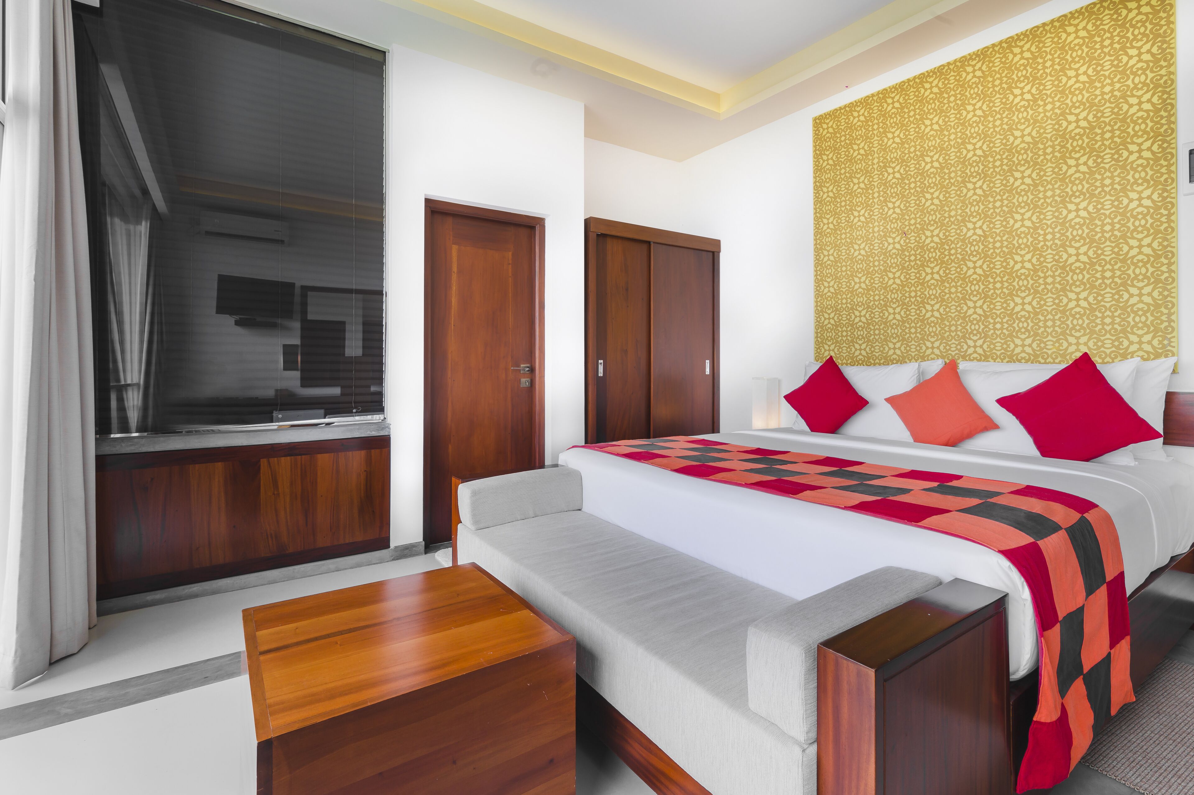 A hotel room with a bed, a sofa, a wooden table, and a wardrobe.