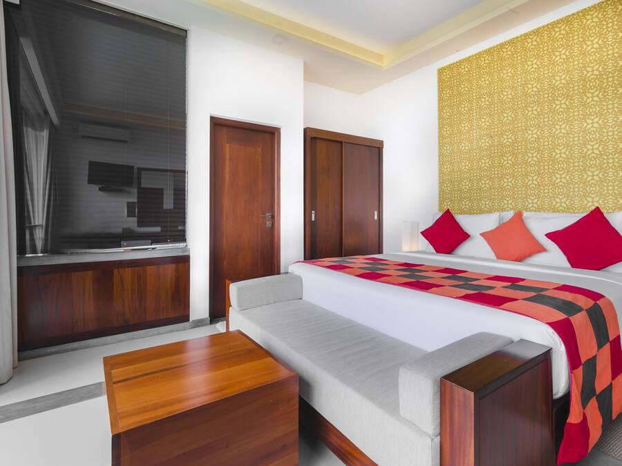 Una habitación de hotel con cama, sofá, mesa de madera y armario.