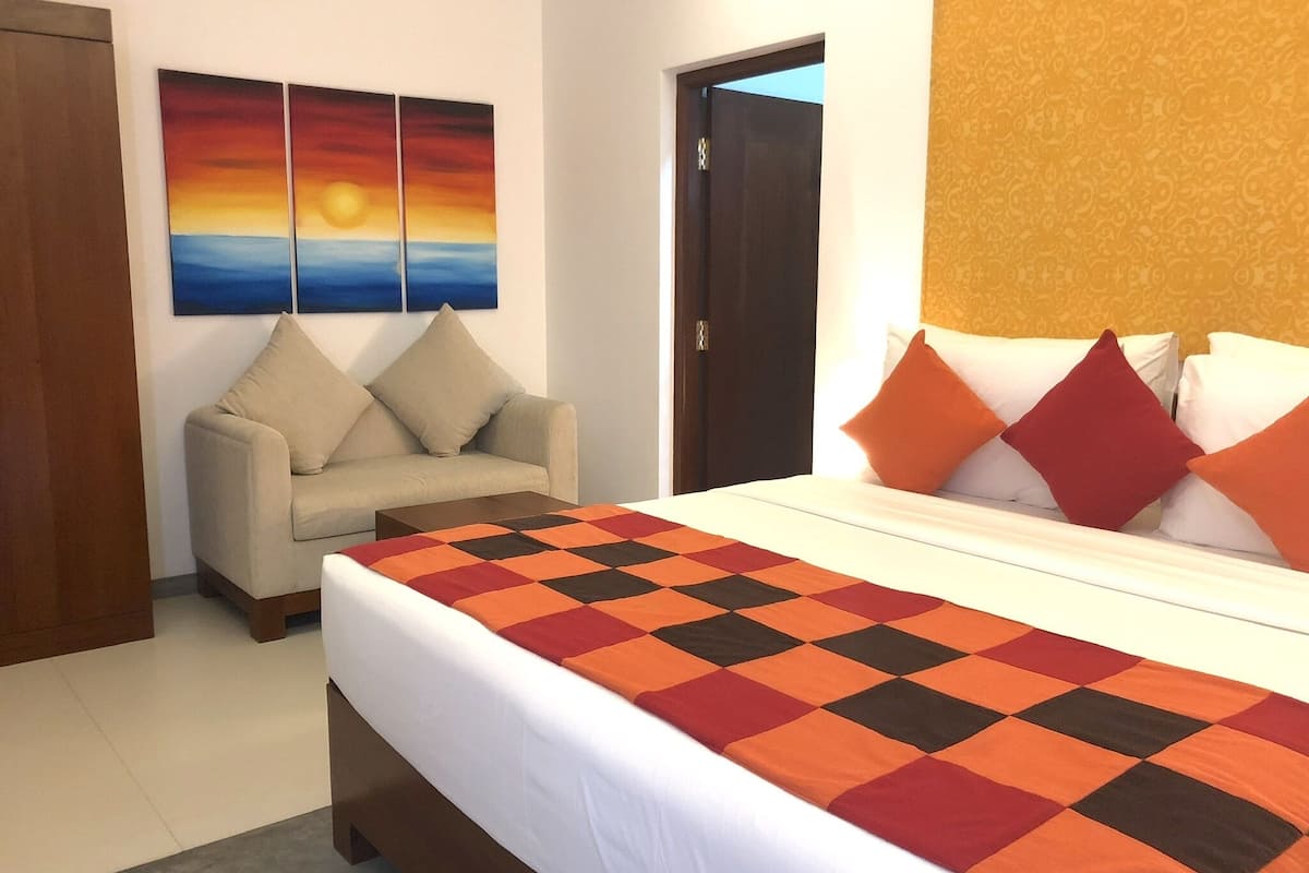 A hotel room with a bed, a sofa, and a painting on the wall.